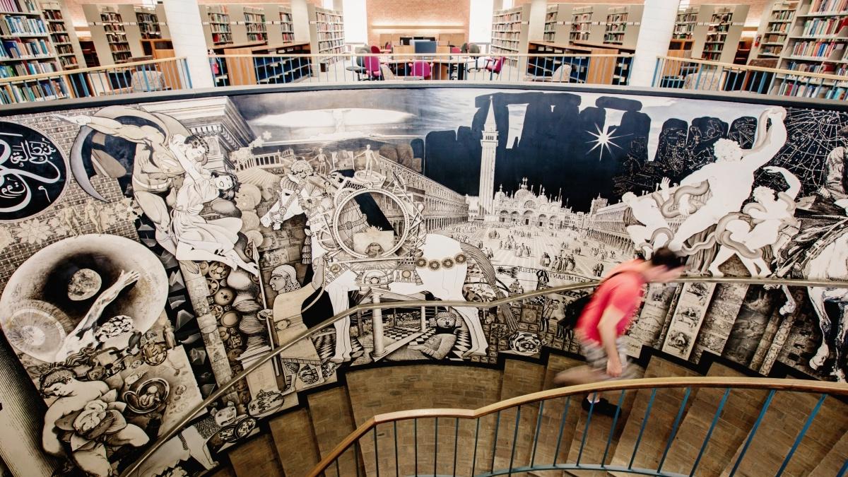 学生爬上科茨图书馆装饰有壁画的螺旋楼梯井